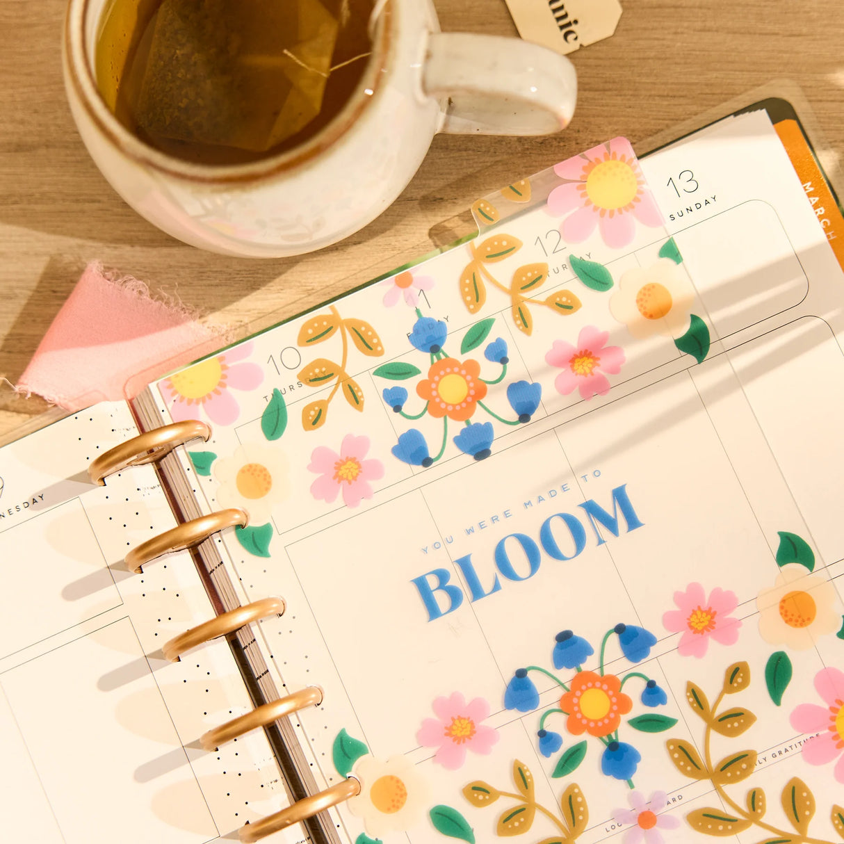 Floral-themed planner with a cup of tea on a wooden surface featuring the Happy Planner Golden Garden Classic Dashboard Pack