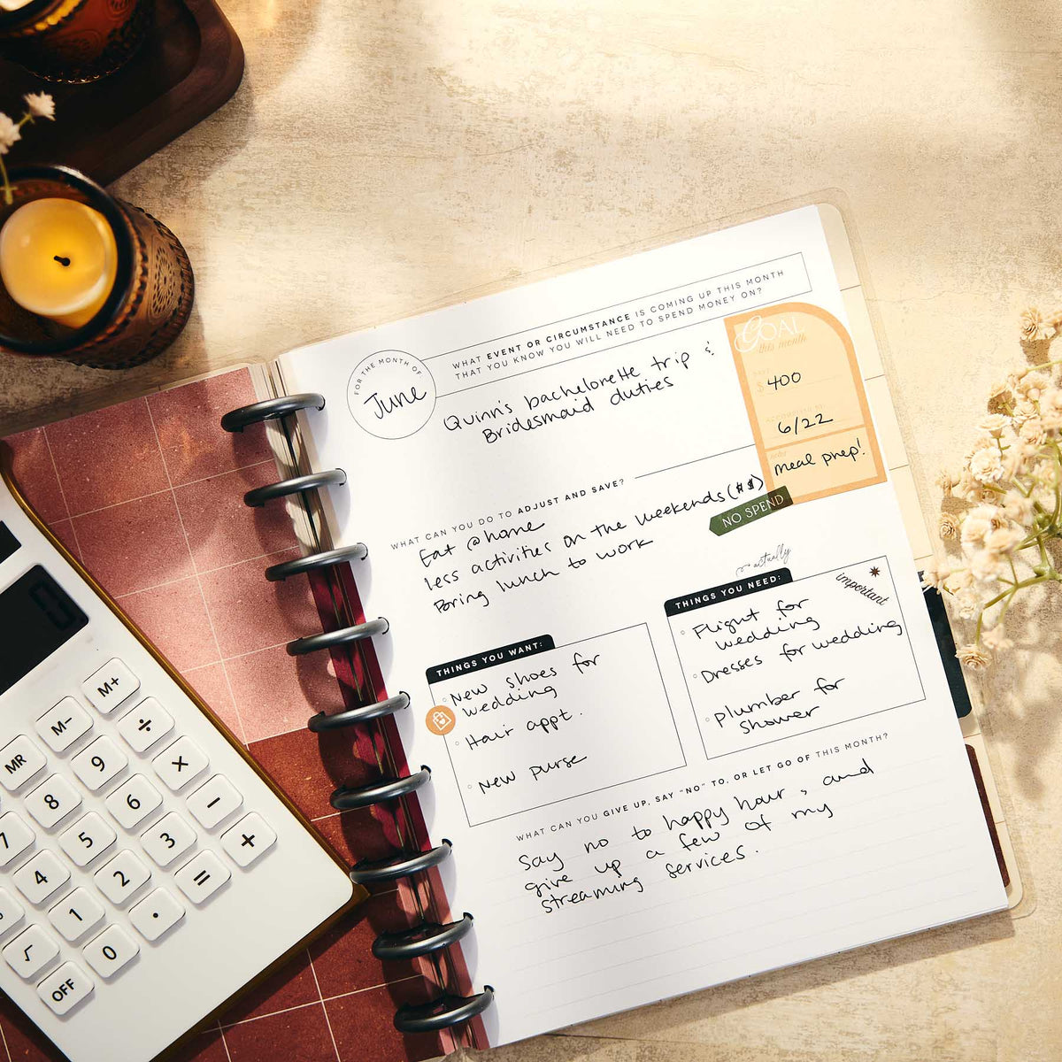 Open Amber & Oak journal with handwritten budget prompts beside a calculator and candle