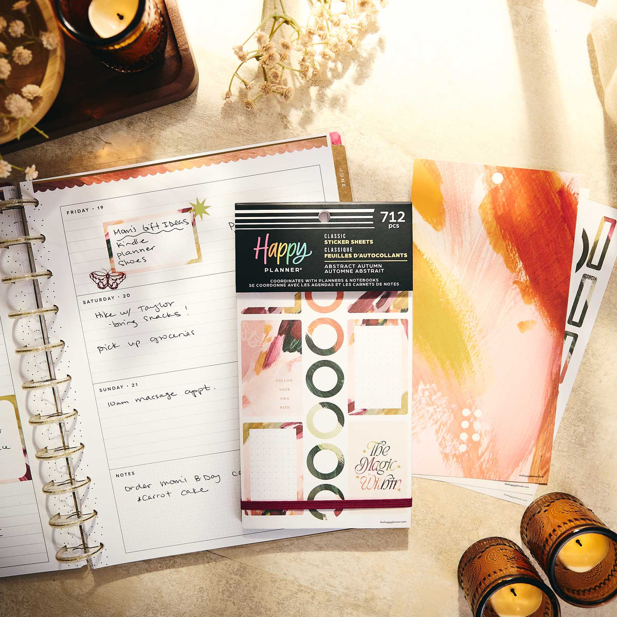 A styled flat-lay of a Happy Planner sticker set, featuring a package of abstract sticker sheets in the Classic Sugar Rush flavor, displayed next to an open spiral planner showing a decorated weekly page.