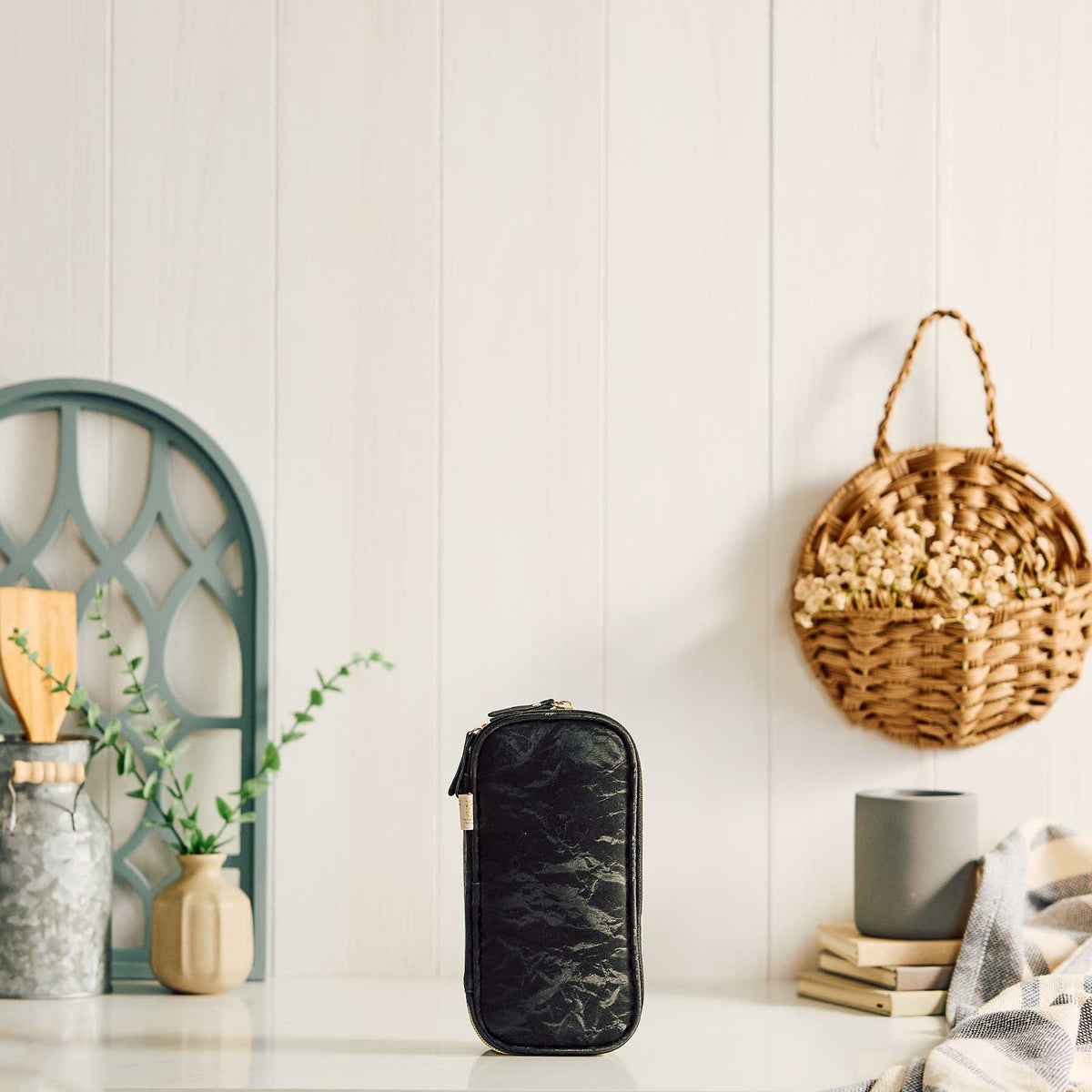 Happy Planner Onyx pouch standing on a tabletop beside books and woven decor