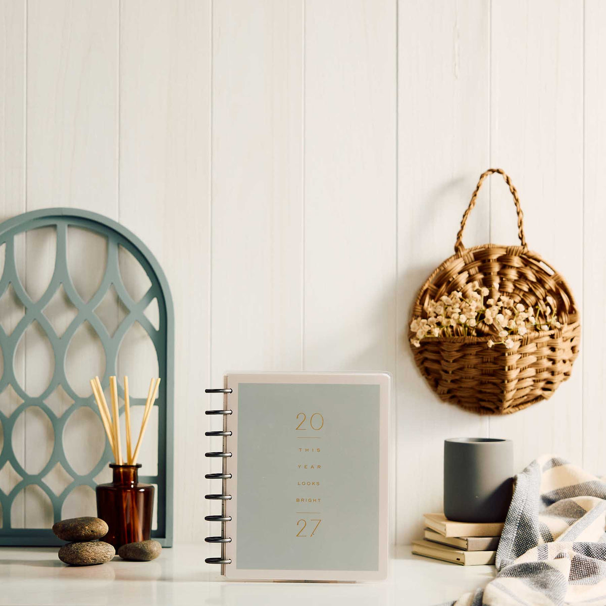 Hushed Hues planner with sage cover and black discs on a desk beside home decor