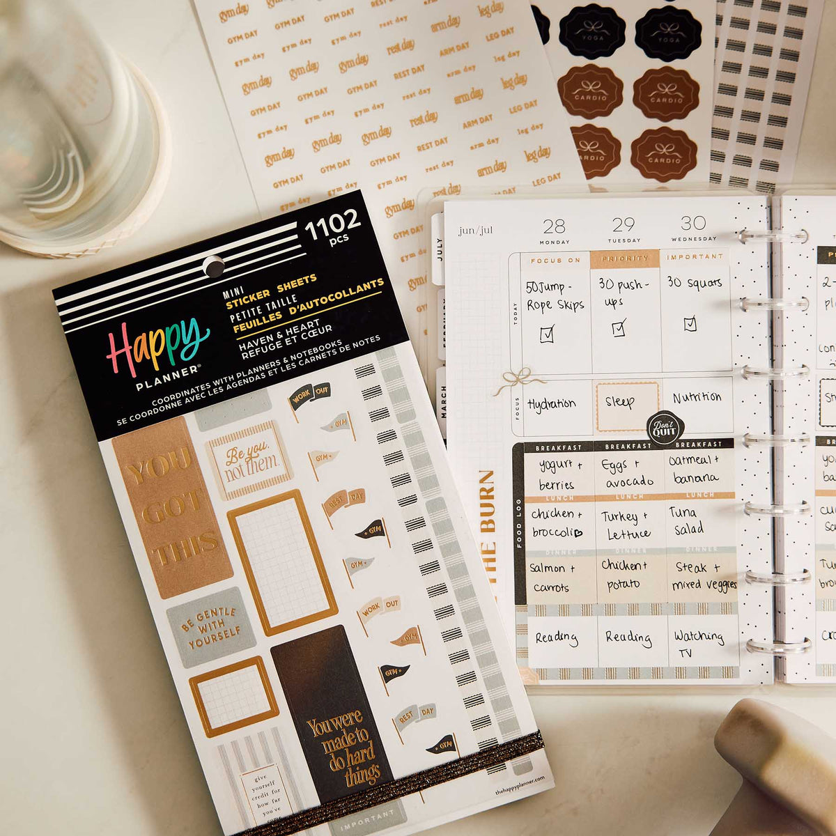 Haven & Heart Fitness sticker book beside a weekly fitness planner with workout and meal notes