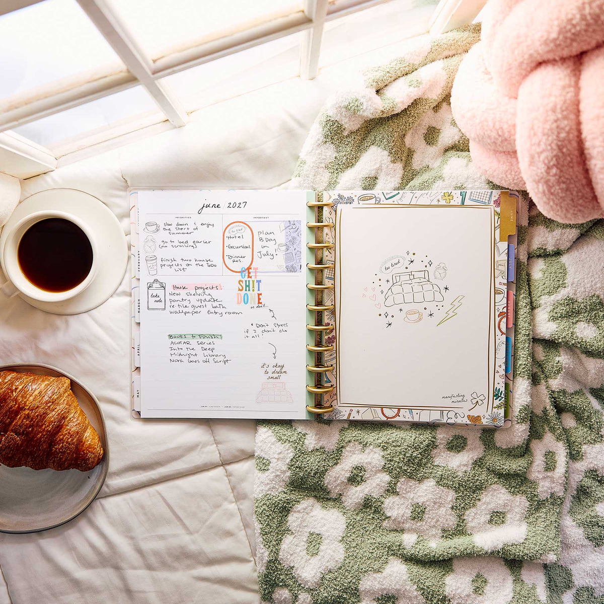 Pajama Plans Big planner with handwritten plans beside coffee and a croissant