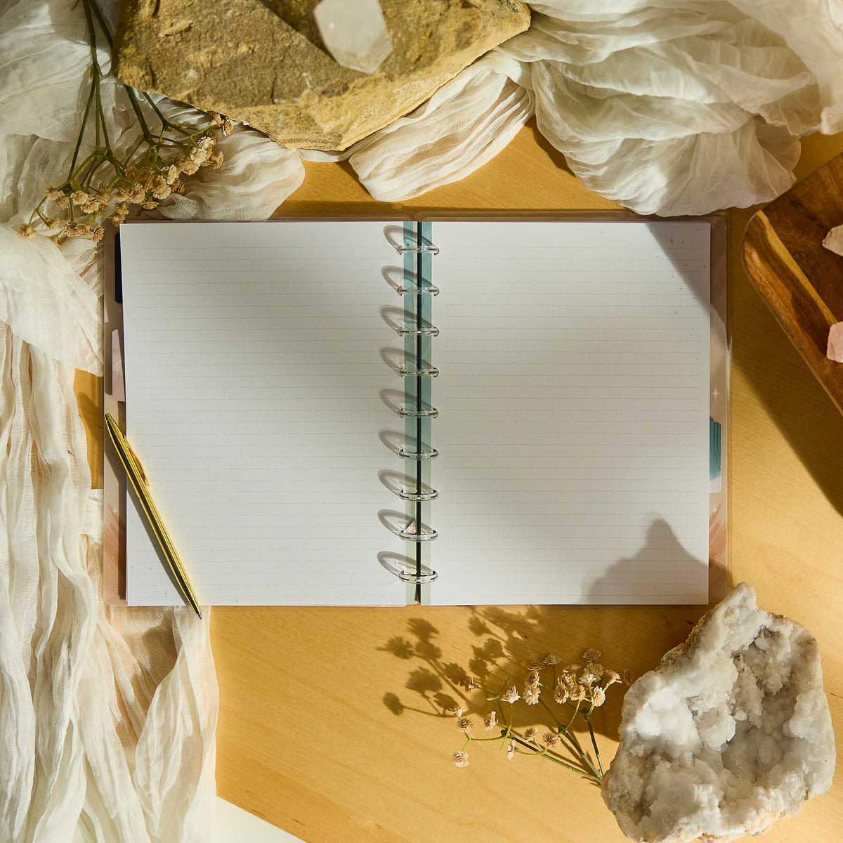 Starlit Glow notebook open on a wooden surface beside dried flowers and crystals