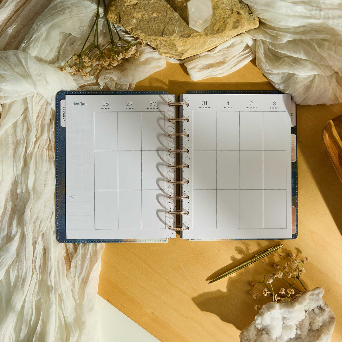 Starlit Glow planner blank weekly spread with metallic discs on a sunlit desk