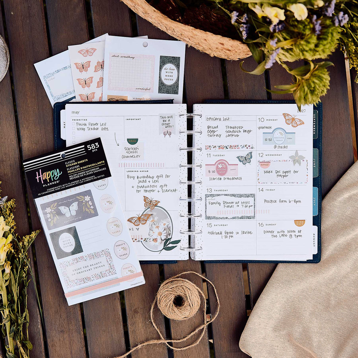 Happy Planner Wildflower Daydream sticker book beside a decorated weekly spread, flowers and twine