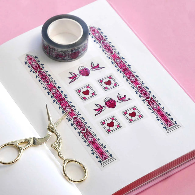 Decorative paper with pink floral patterns, scissors, and tape on a pink background