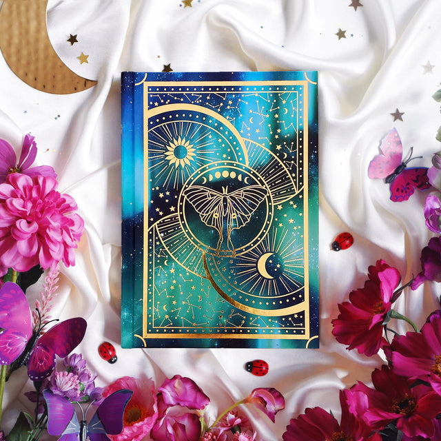 Luna Moth A5 Journal notebook with celestial design surrounded by flowers and butterflies on a white fabric background
