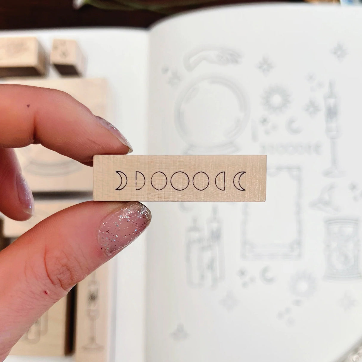 wooden stamp with moon phase design in front of a white surface with patterns.