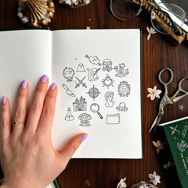 notebook with black Book Genre Stamps on a wooden surface with stationery items.