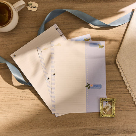 Set of stationery items including paper, a ribbon, and a cup on a wooden surface.