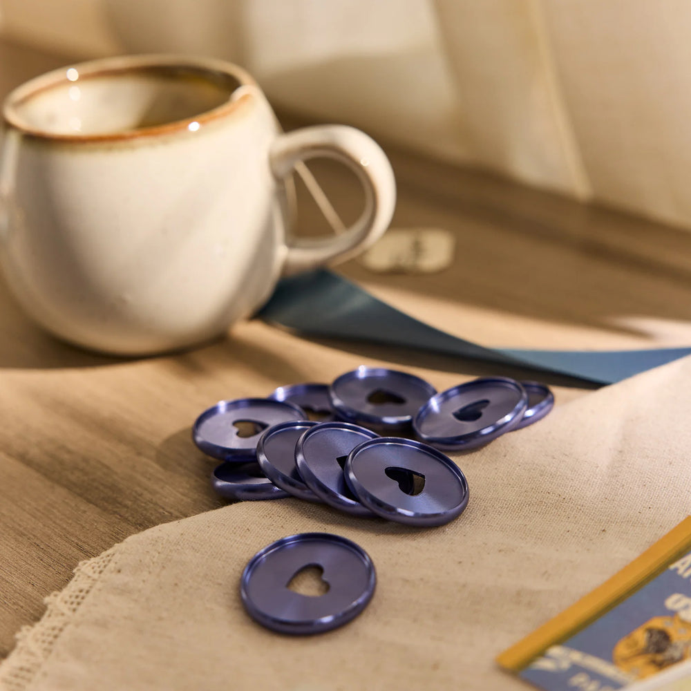 Happy Planner Forget Me Not Heart Metal Disc Set on a beige surface with a white mug in the background