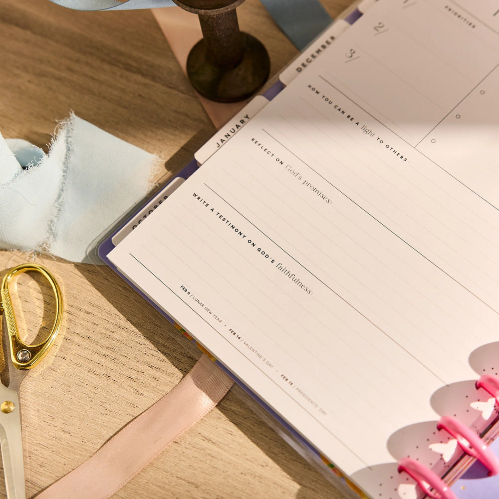 Open planner on a wooden surface with a pair of scissors and fabric
