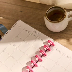 Pink planner with a mug of tea in the background