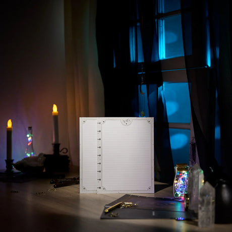 Notebook with lined pages on a dark background with candles and decorative lights