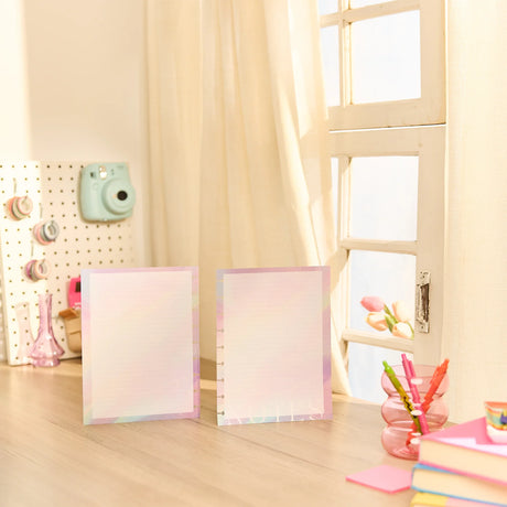 Two colorful notepads on a desk with stationery items in a bright room.