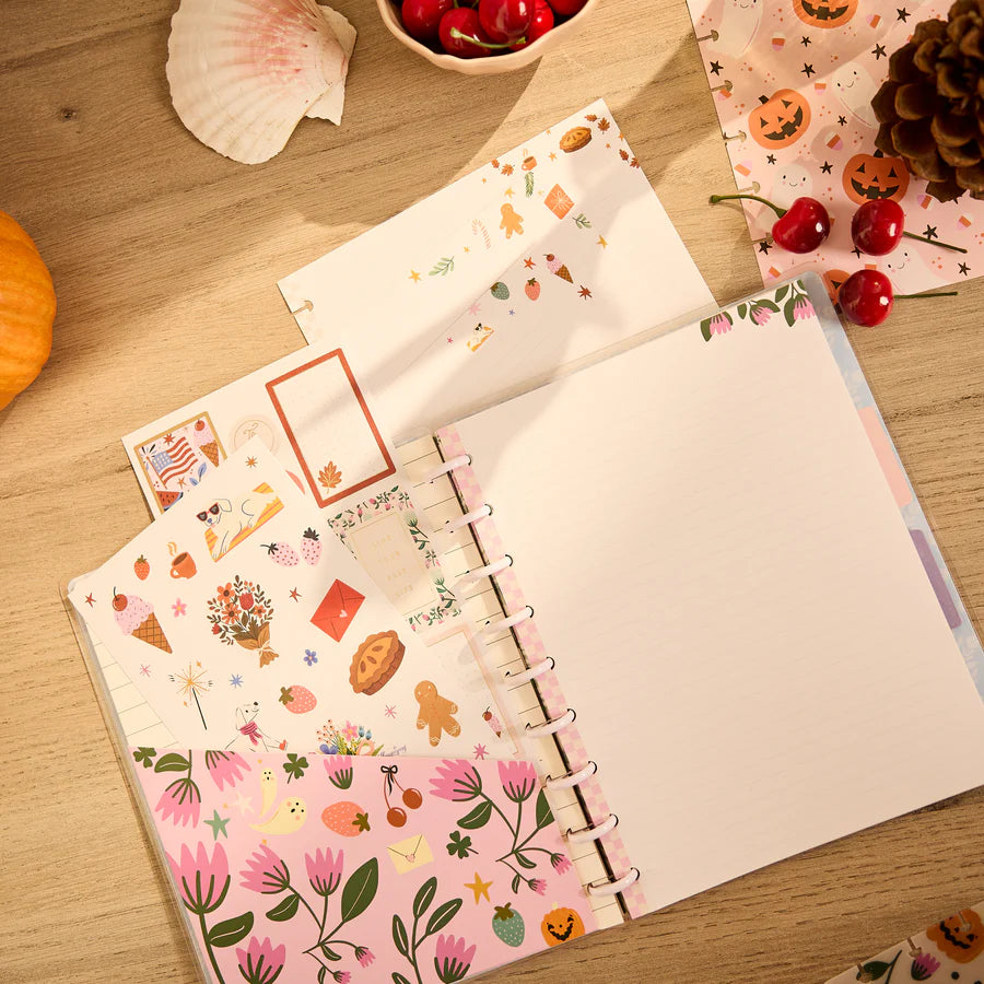 Notebook with decorative pages on a wooden surface with autumn-themed items.