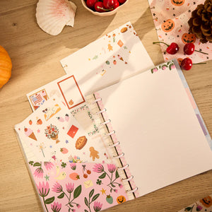 Notebook with decorative pages on a wooden surface with autumn-themed items.