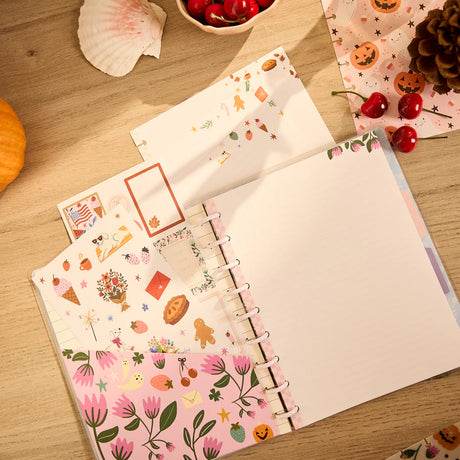 Notebook with decorative pages on a wooden surface with autumn-themed items.