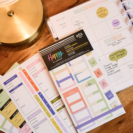 Happy Planner stickers on a wooden surface with a lamp in the background