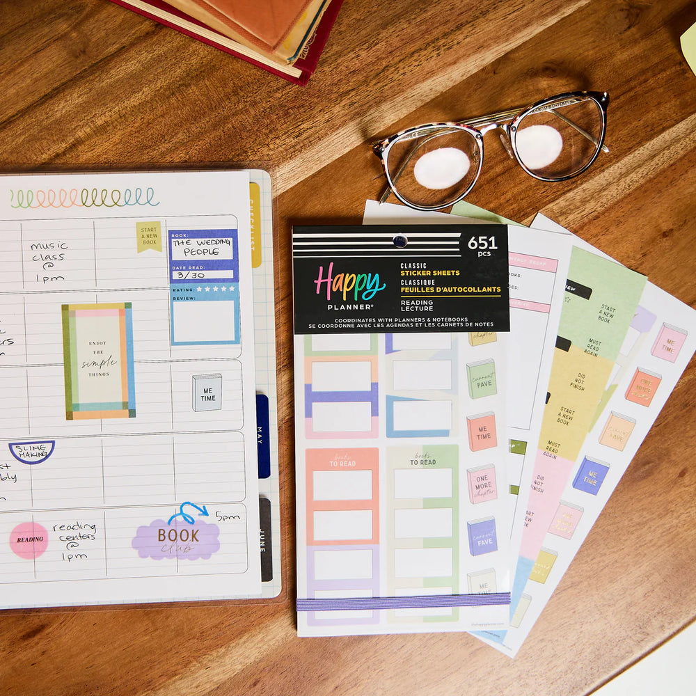 Planner with stickers and glasses on a wooden surface