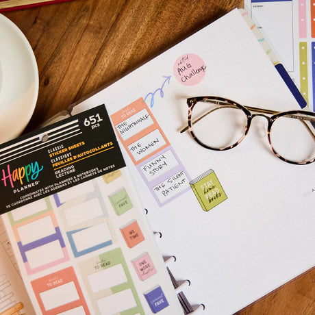 Happy Planner stickers with a planner and glasses on a wooden surface