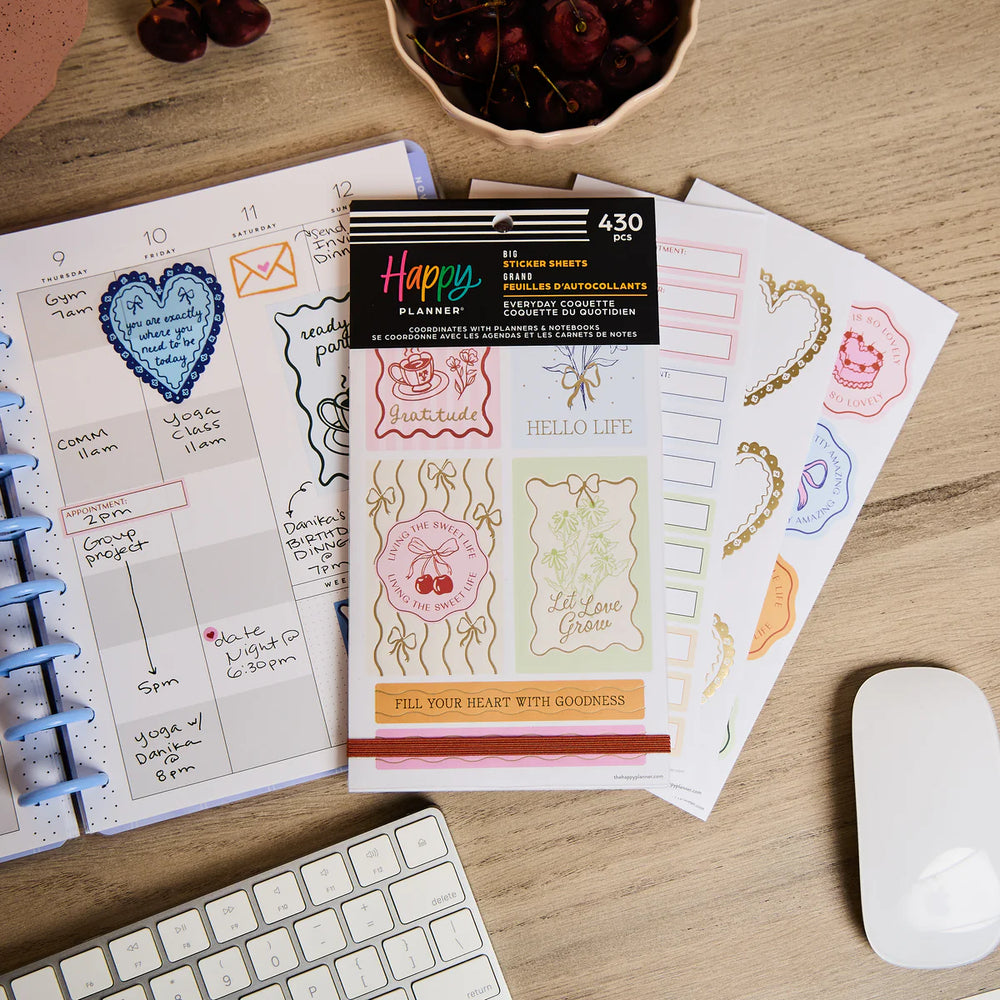 Happy Planner Everyday Coquette Big Sticker Book and planner on a desk with a keyboard and mouse.
