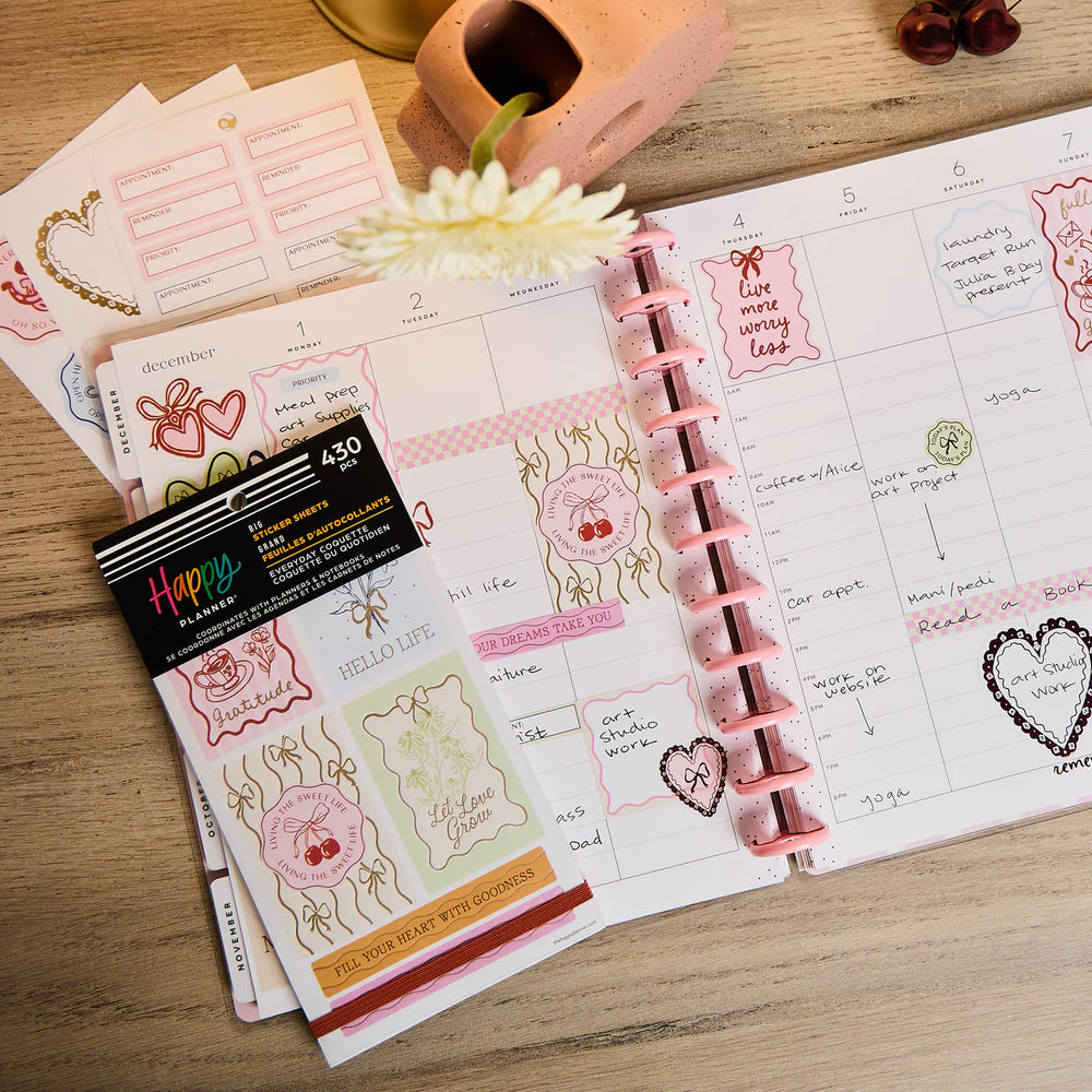 Planner with Happy Planner Everyday Coquette Big Sticker Book and a card on a wooden surface
