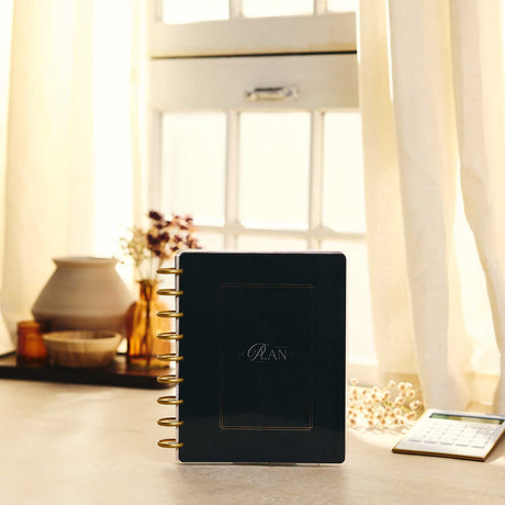 Amber & Oak black disc-bound Budget Planner on a sunlit desk