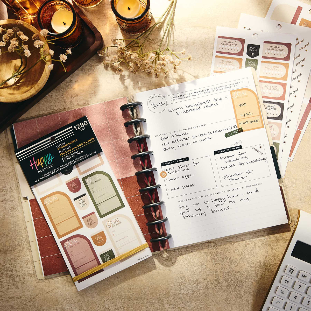 Happy Planner Amber & Oak Budget sticker book on a disc-bound planner beside candles and bill labels