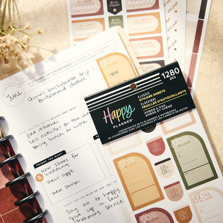Close-up of Amber & Oak Budget savings stickers beside handwritten financial plans