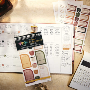 Amber & Oak Budget sticker book on an expense tracking spread with sticker sheets and a calculator