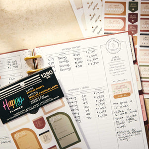Happy Planner Amber & Oak Budget sticker book beside handwritten income and expense tracking pages