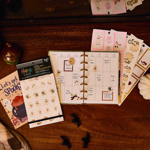 Ghosty Season ghost stickers beside a Halloween-themed disc-bound planner on a wooden desk