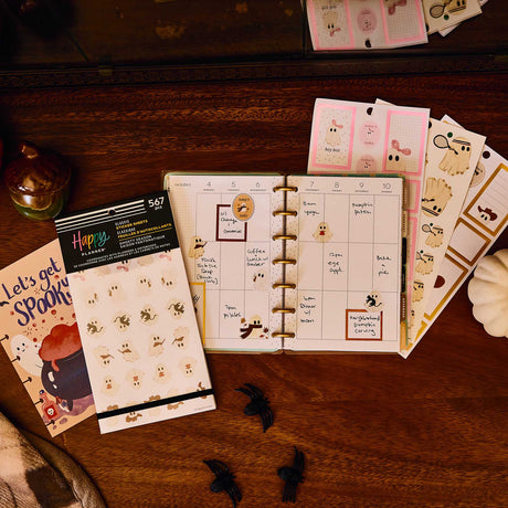 Ghosty Season ghost stickers beside a Halloween-themed disc-bound planner on a wooden desk