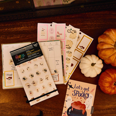 Ghosty Season stickers beside an open planner and Halloween journal with pumpkins on a wooden table