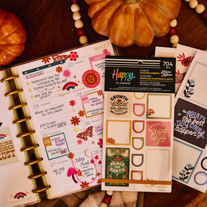 Bright Seasons sticker book and floral sheets on a decorated weekly planner beside pumpkins and a beaded garland