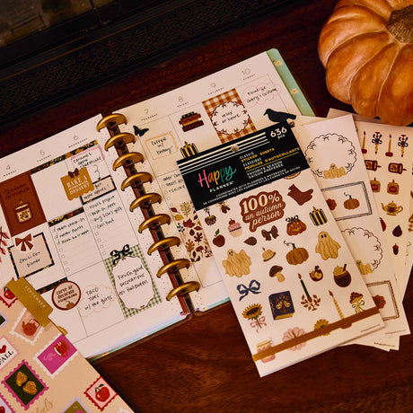 Open Happy Planner with autumn stickers, Favorite Season sticker book and decorative sheets beside a pumpkin
