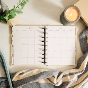 Haven & Heart planner monthly spread beside a candle and greenery
