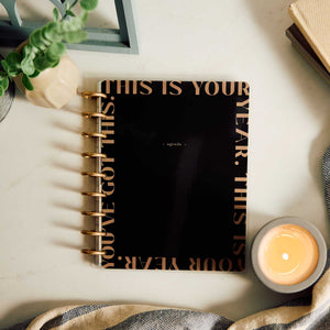 Happy Planner Haven & Heart Classic daily undated planner - black cover beside a coffee cup and plant