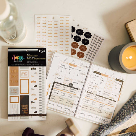 Mini fitness sticker book and sticker sheets beside an open disc-bound fitness planner and candle