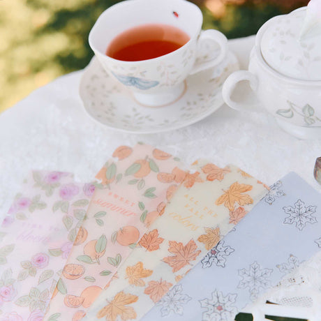 Four Seasonal Sidewalks snap-in bookmarks fanned out beside a floral teacup