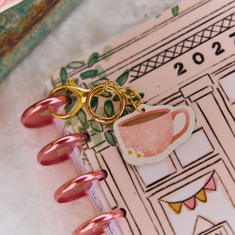 Close-up of the pink floral Coffee Planner Charm hanging from a Happy Planner disc