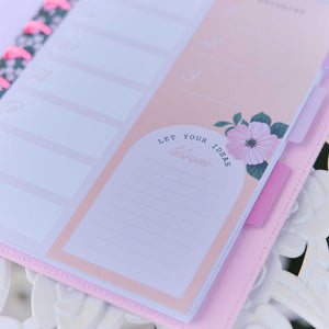 Petal Press pink floral planning page with pastel daily sections
