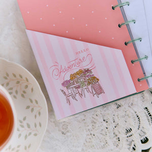 Seasonal Sidewalks Hello Adventure card in a disc-bound planner beside a floral teacup