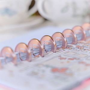 Latte coffee cup metal discs on a planner with printed pages and colourful designs