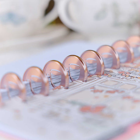 Latte coffee cup metal discs on a planner with printed pages and colourful designs