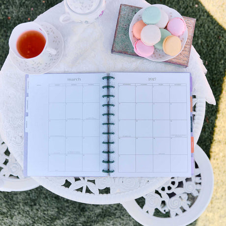 Happy Planner Hive and Bloom monthly spread beside tea and pastel macarons