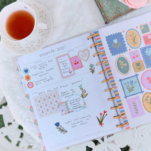 Little Garden monthly spread decorated with floral stickers and handwritten notes beside tea