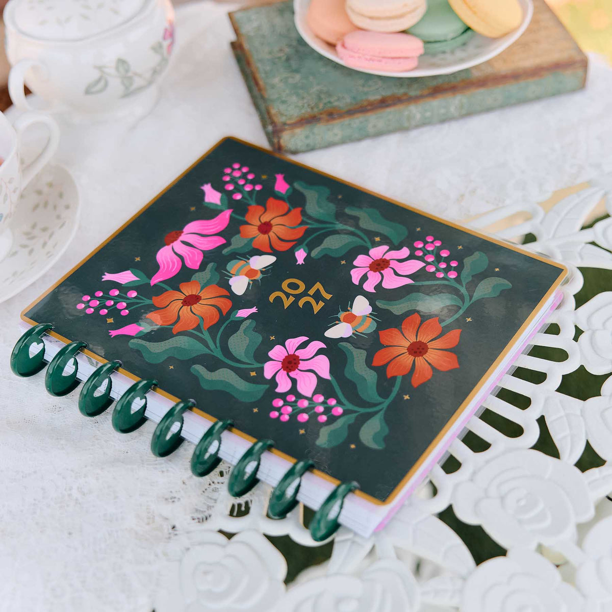 Happy Planner Hive & Bloom Classic Vertical Planner 2027: Floral cover and green discs on a decorative table